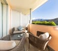 outdoor seating area with table, couch, pillows, flowers, large windows, view of mountains