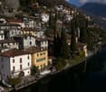 Cluster of residential houses, terraced hillside, mountain view, waterfront with boats