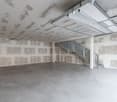 Empty room, concrete floor, unfinished walls, metal staircase, metal garage door