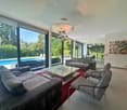 Spacious living room with floor-to-ceiling windows, modern furniture, outdoor swimming pool, garden views