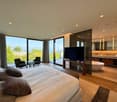 Large bed, modern design, glass windows, large bathroom with bathtub, armchairs, view of the outside, television