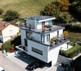 modern design, white exterior, 2 balconies, solar panels on roof, car in driveway