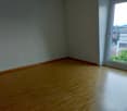 Empty room with hardwood flooring, light-colored walls, and a large window overlooking the city skyline.