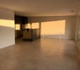 Large open space, tiled flooring, kitchen area with countertop and cabinets, sliding glass door leading to balcony