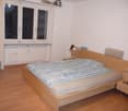 Bedroom: double bed, headboard, nightstand, radiator, large window, chair