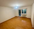 Empty room with wooden floors, white walls, glass doors, and a balcony