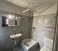 Bathroom with white walls, tiled floor, single sink, separate bathtub, white toilet, and silver shower