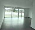 Empty room, white walls, large windows, black tile floor, sliding doors leading to a balcony.