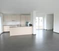 Modern open-plan kitchen, living and dining room, grey tile floor, white cabinets, no appliances