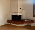 Corner fireplace with white and brown tiles, wooden floor, white walls