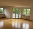 Empty room with wooden floor, sliding doors leading to balcony, white walls, large windows
