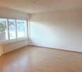 an empty room with wooden floors and a large window
