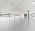 Large empty room, white tiled floor, high ceiling, multiple windows
