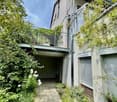 Facade of a house with a balcony, plants, garden, and brick path.