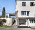 white modern building, glass windows, balcony, garage with open doors