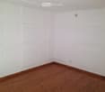 Empty room with wooden floors and white walls, square and rectangular acoustic panels mounted on walls.