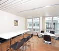 modern room with round tables, square tables, glass windows, wooden floor, white wall