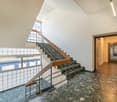 Wooden handrail, metal handrail, large window, tiled flooring, wooden staircase