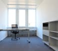 Modern office room with desk, chair, and shelves, large windows providing natural light