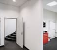empty room with white walls, black floor, two open doors leading to a staircase, small red cabinet in the corner