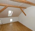 empty attic room with wooden beams, windows, and a skylight