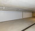 underground parking garage with two car parking spaces, light ceiling, drainage system