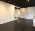 Empty room with white walls, black tiled floor, large mirror, and ceiling lights