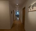 Long hallway with hardwood floors, white walls, recessed lighting, and a decorative world map mural on the wall.