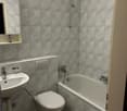 Bathroom with white tiles, bathtub, toilet, sink, mirror, and shower