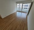Hardwood floors, white walls, sliding glass doors leading to a balcony, power outlets on the wall
