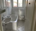 white tiles, bathtub, sink, toilet, mirror, shower head