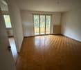 Empty room, hardwood floors, glass sliding doors leading to a balcony, radiator, open doorway