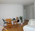 table with 4 chairs, couch, white walls, floor, potted plant
