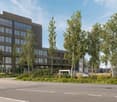 modern office building, multiple floors, glass windows, parking area, greenery