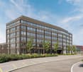 Modern office building with glass windows, brown facade, parking area in front