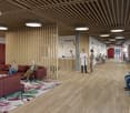 large room, wooden floor, wooden ceiling, large windows, red curtains, reception desk, people sitting on chairs, people standing, people reading