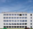 4 story office building, modern style, white facade, large windows, two cars parked in front