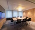 conference table, black chairs, mounted TV, white curtains