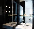 Black tiled walls, white countertops, shower enclosure, two sinks, mirrored cabinets, modern fixtures