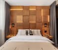 Wooden wall, lit wall panels, large bed, pillows, blanket, nightstands, candles, statue, curtains