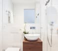 modern bathroom with white marble floor, glass shower enclosure, white sink, white toilet