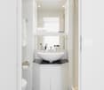 compact bathroom, white sink, silver faucet, mirror, white toilet, black slippers