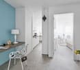 Minimalist decor, blue accent wall, white desk, white chair, white lamp, clear plastic stool, gray floor