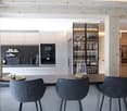 modern kitchen, gray bar stools, black countertops, white cabinets, open shelving for wine glasses