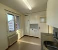 Spacious kitchen with modern appliances, white cabinets, large sink, granite countertop, radiator, large window