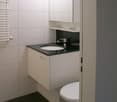 white tiles, black tiles, white sink, black sink top, white toilet, white cabinet, white towel radiator