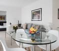 open layout, glass dining table, grey sofa, glass side tables, framed art, white furniture, tiled floor