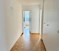 Hallway, wooden parquet floor, white walls, open door, leading to other rooms, cabinet