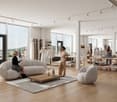 Large open-concept retail space with high ceilings, large windows providing a view, hardwood floors, and modern furniture and decor. The space includes a seating area with a large gray sofa and coffee table, as well as clothing racks and displays througho