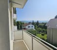 Balcony with a view of the surrounding neighborhood, including houses, trees, and mountains in the distance.